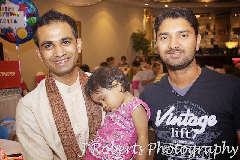 Father and uncle with sleeping 1 year old at her party - party photography sydney